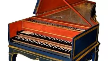 Front view of an 18th-century double manual harpsichord by Jean Goermans, showing decorated soundboard, blue-and-gold exterior, and original seven-legged stand